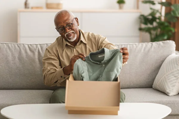 Senior African Man Unpacking Box Après des achats en ligne réussis à l'intérieur — Photo