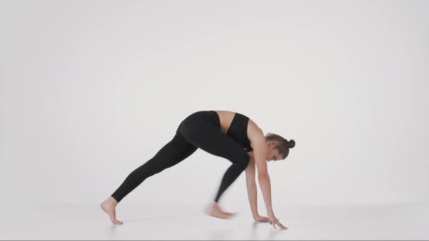 Junge flexible praktizierende Trikonasana und Downward Dog Posen, die ihren Rücken über weißem Studiohintergrund strecken — Stockvideo