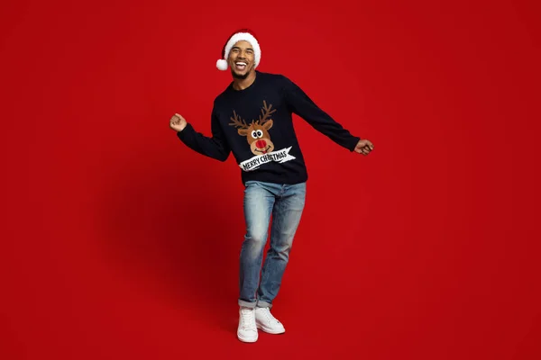 Vrolijke zwarte man in Santa hoed dansen op rood — Stockfoto