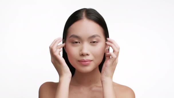 Retrato de mujer asiática haciendo masaje facial sobre fondo blanco — Vídeos de Stock