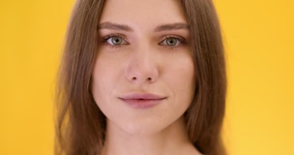Natuurlijke schoonheid. close-up portret van jonge vrij rustige blanke vrouw op zoek naar camera, gele studio achtergrond — Stockvideo