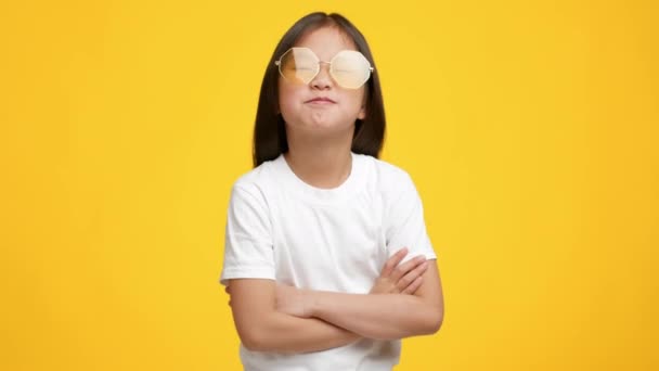 Legrační korejské holčička nosí sluneční brýle pózování přes žluté pozadí — Stock video