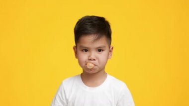 Küçük Asyalı Çocuk Sakız Çiğneyip Çiğniyor Sarı Arkaplanda
