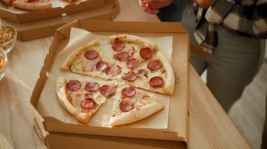 Çeşitli arkadaşların ellerinin salamlı taze pizzayı alıp evde birlikte öğle yemeğinin tadını çıkardığı en iyi manzara.