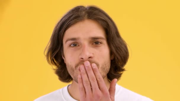Skickar dig min älskade. Porträtt av ung flirtig kille skicka slag kyss och blinkar till kameran, gul studio bakgrund — Stockvideo
