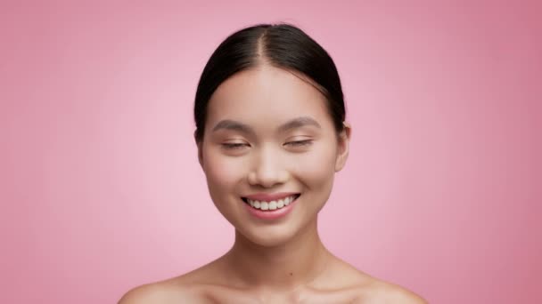 Koreanerin lächelt in die Kamera und posiert hemdlos vor rosa Hintergrund — Stockvideo