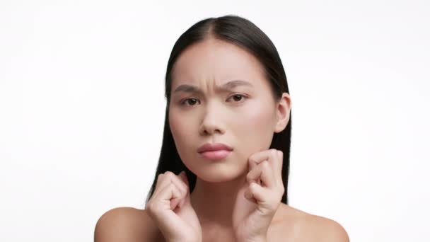 Discontented Asian Female Touching Face Skin On White Background — Stock Video