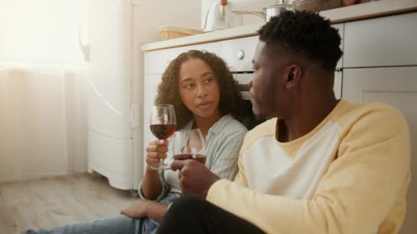 Καθημερινός έρωτας. Νεαρό ζευγάρι αφροαμερικανών ερωτευμένων κάθεται στο πάτωμα της κουζίνας, απολαμβάνοντας το κρασί και μιλώντας, ελεύθερος χώρος — Αρχείο Βίντεο