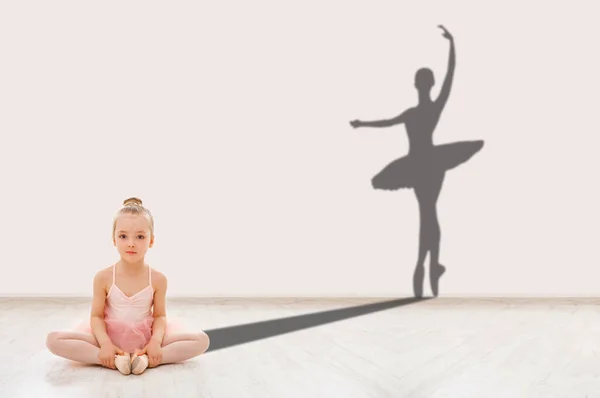 Маленькая балерина на полу и форма взрослой танцовщицы позади — стоковое фото