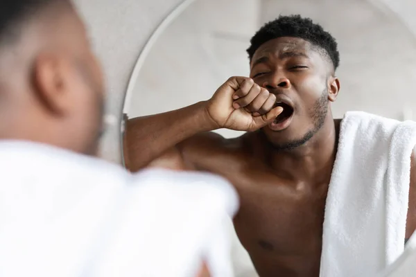 Sonnolento afroamericano uomo sbadigliare in piedi vicino specchio in bagno — Foto Stock