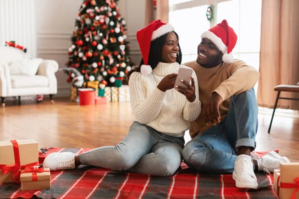 Glad festlig svart familj med mobiltelefon välja gåvor på Xmas — Stockfoto