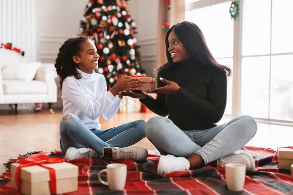 Portrait of happy black family celebrating Christmas giving present