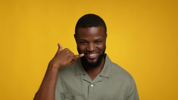 Ruft mich an. Schöner schwarzer Mann zeigt Handygeste und nickt — Stockvideo