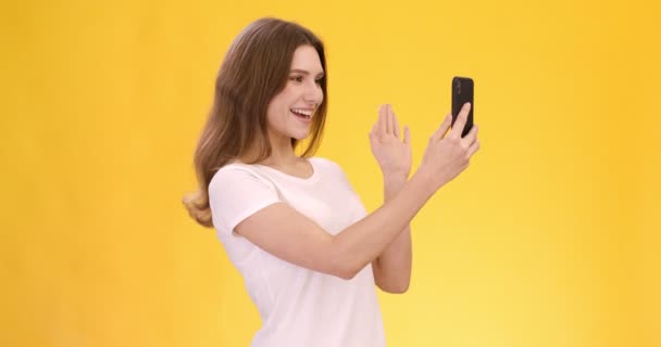 온라인 커뮤니케이션. 젊은 여성 이 핸드폰으로 채팅하는 영상입니다. 서로 손을 흔들고 대화를 나누는 것 — 비디오