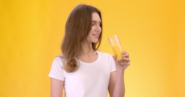 Bebida natural fresca. Estudio retrato de joven alegre dama caucásica bebiendo jugo de naranja orgánico de vidrio — Vídeo de stock