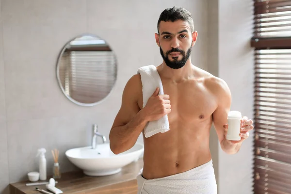 Bonito jovem de pé com shampoo e desodorizante garrafa — Fotografia de Stock