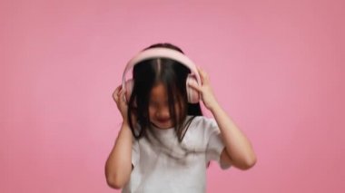 Kulaklık takan Japon Kız Pembe Arkaplanda Dans Eden Müzik dinliyor