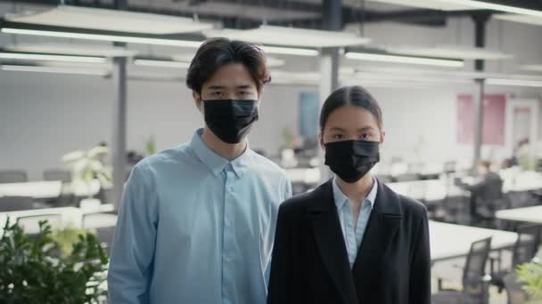 Japanische weibliche und männliche Kollegen mit Masken posieren im Büro — Stockvideo