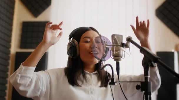 Новый трек. Энергичная азиатская исполнительница женской песни в музыкальной студии — стоковое видео