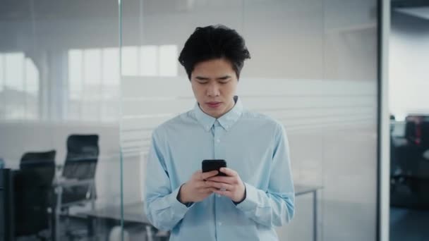 Coreano negócio cara usando Smartphone navegação Internet andando no escritório — Vídeo de Stock