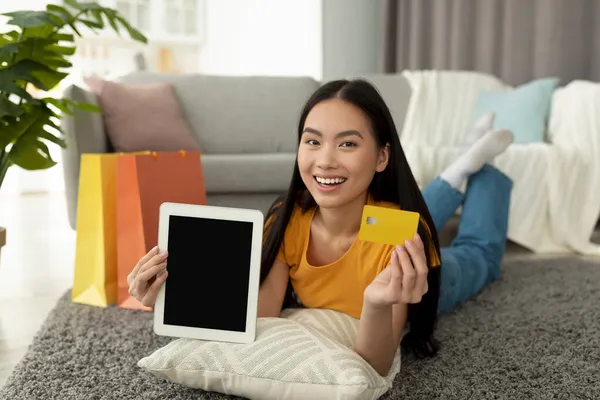 Happy asian woman showing tablet with blank screen and credit card, shopping in web store, demonstrating mockup — Stock Photo, Image