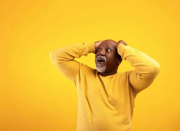 Verbazingwekkende emotionele senior zwarte man houdt zijn hoofd in shock, kijkend naar kopieerruimte voor uw tekst of advertentie — Stockfoto