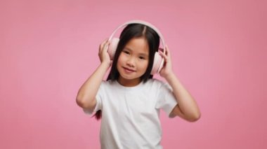 Koreli Kız Müzik Dinleyen Pembe Arkaplan Üzerinde Kulaklık Giyen