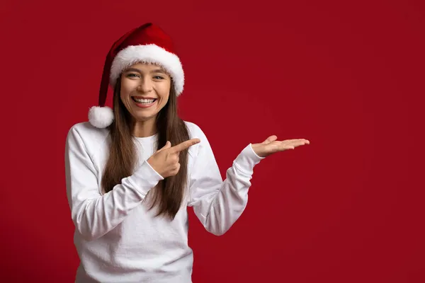 Podívej se na tohle. Šťastná žena v Santa Klobouk ukazující na otevřené dlani — Stock fotografie