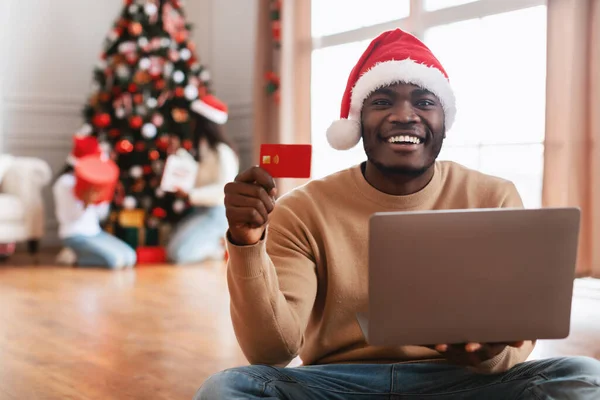 クリスマスオンラインショッピング。クレジットカードを示すラップトップを使用して笑顔男 — ストック写真