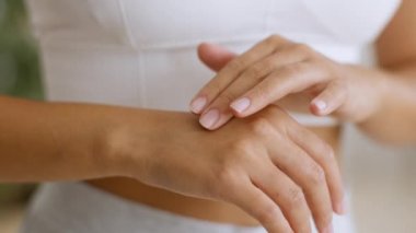 Cilde önem ver. Genç bayanın avuçlarına nemlendirici krem sürerken ve ellerini şımartırken yakın plan fotoğrafı.