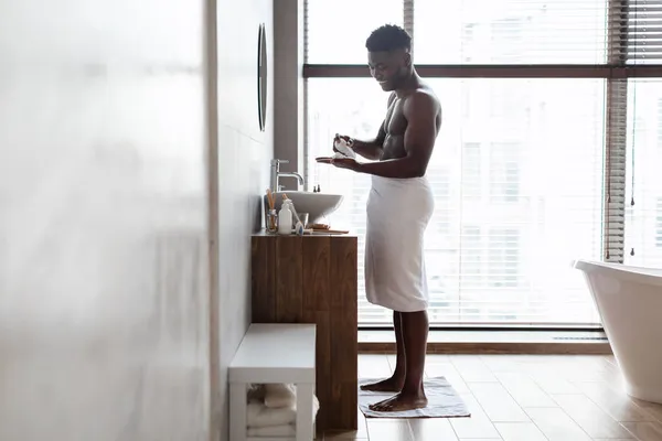 Zwarte man toepassen scheerschuim op de hand staande in de badkamer — Stockfoto