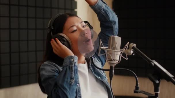 精力充沛的亚洲女歌手头戴耳机在音乐工作室演唱新歌 — 图库视频影像