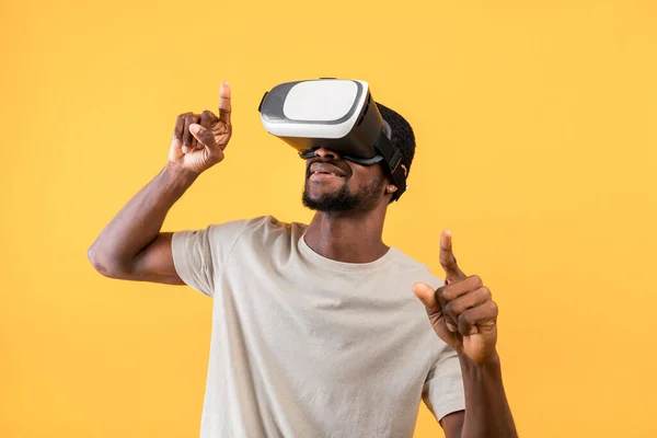 Jonge zwarte man met VR bril, ervaren augmented reality en gebaren tijdens het spelen van videospelletjes — Stockfoto