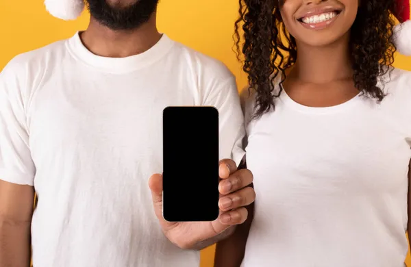 Jovem casal afro-americano mostrando smartphone com tela em branco, demonstrando site ou aplicativo, close-up — Fotografia de Stock