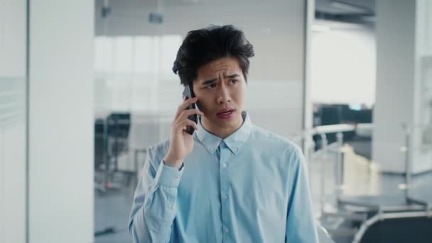Asijské tisíciletí člověk mluví na mobilním telefonu stojící v kanceláři — Stock video