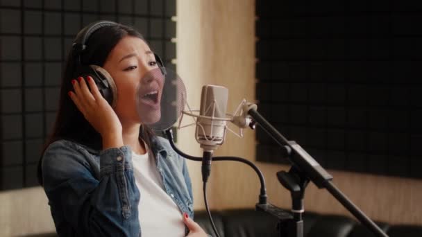 Talentuoso asiatico cantante donna indossare cuffie canto canzone a microfono in studio — Video Stock