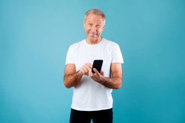 Mutlu, olgun bir adam cep telefonunu stüdyoda kullanıyor.