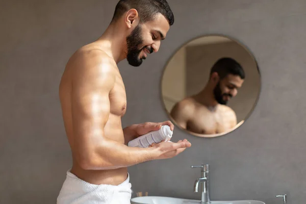 Tipo seguro aplicando espuma de afeitar de la botella en la mano — Foto de Stock