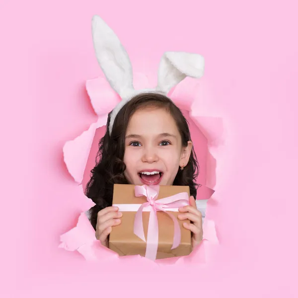 Feliz animado caucasiano adolescente menina com boca aberta com orelhas de coelho se alegra no presente na caixa — Fotografia de Stock