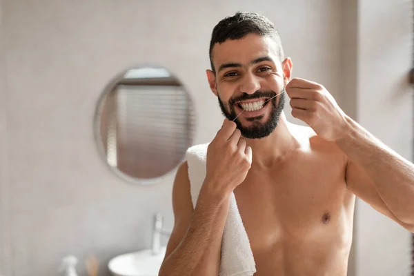 Jovem árabe cara usando fio dental no banheiro — Fotografia de Stock