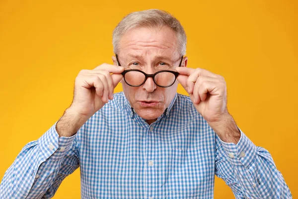 Mature man squinting wearing eyeglasses, looking at camera