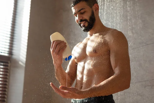 Bello giovane uomo versando shampoo su palma — Foto Stock