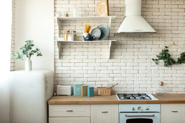 Modern Scandinavian kitchen interior with light furniture, household items near brick wall. Home decor concept