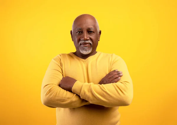 Retrato de positivo sênior afro-americano homem posando com cruzados braços no laranja estúdio fundo — Fotografia de Stock