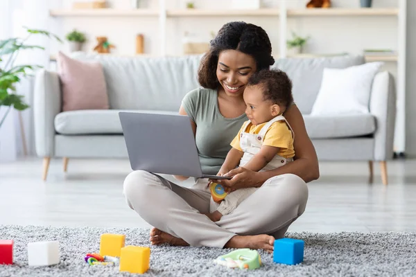Černá maminka ukazuje vývoj videa na notebook na ji dítě doma — Stock fotografie