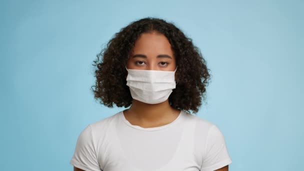 Mujer negra usando máscara facial protectora posando sobre fondo azul — Vídeo de stock