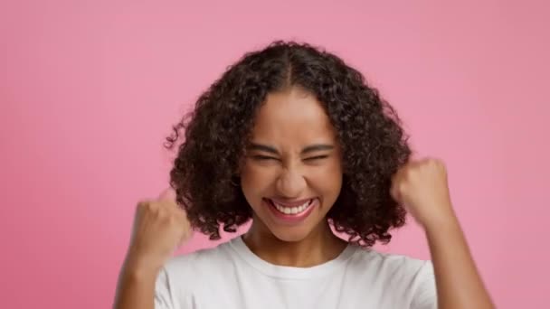 Afrikansk amerikansk kvinna skakar knytnävar Gesturing Ja över rosa bakgrund — Stockvideo