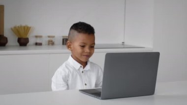 Mesafe öğrenme. Küçük siyah çocuk evde dizüstü bilgisayarda ders alıyor.