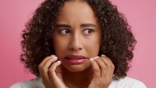 Besorgte schwarze junge Frau, die Angst ausdrückt, das Gesicht berührt, rosa Hintergrund — Stockvideo