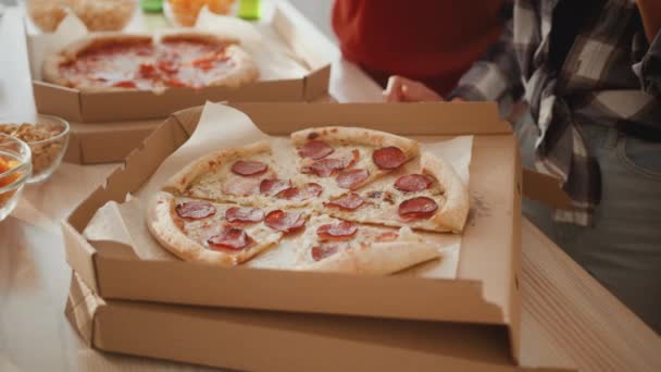 Food delivery service. Close up shot of unrecognizable diverse friends taking pieces of fresh cut pizza from box — Stock Video